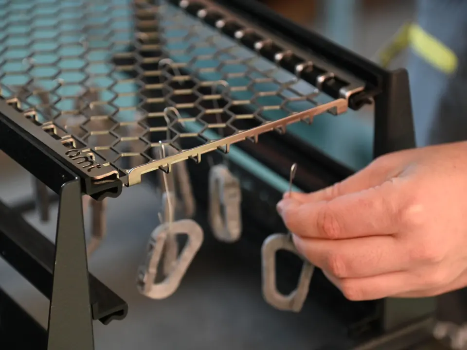 As-printed parts being hung on wire hooks under a smoothing rack