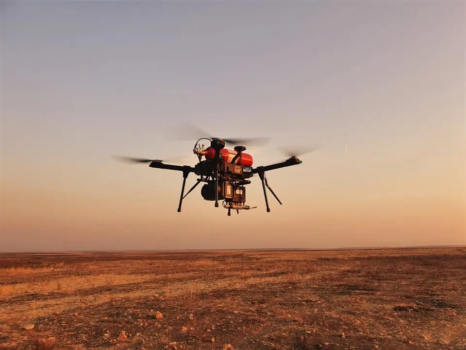 Hydrogen fuel-cell drone in flight low over open desert at dusk